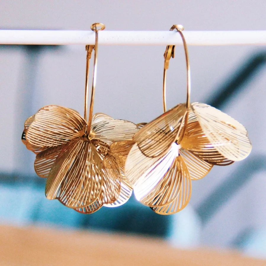 Filigrane Kette mit drei Statement Blumen. In goldene farbe aus robustem Edelstahl, perfekt um aufzufallen und für einen schicken, trendy look. Die Kette liegt auf einem hellen untergrund.
