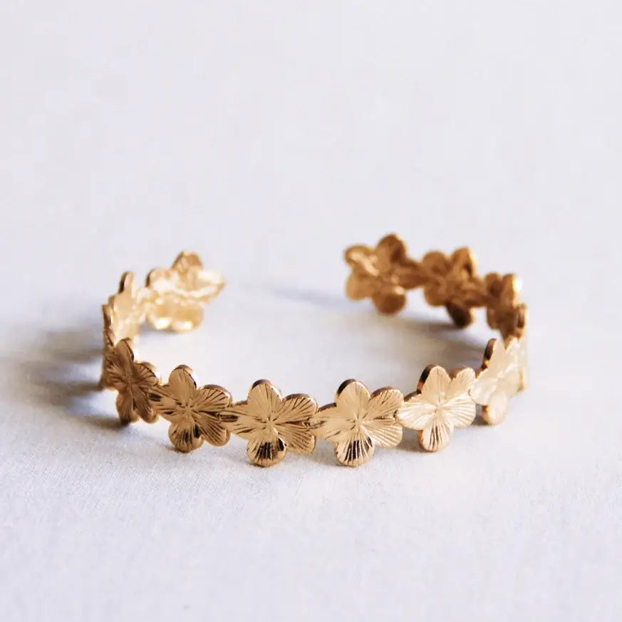 Goldfarbener Armreif mit Blumen aus Edelstahl, ideal für feminine und moderne Looks.