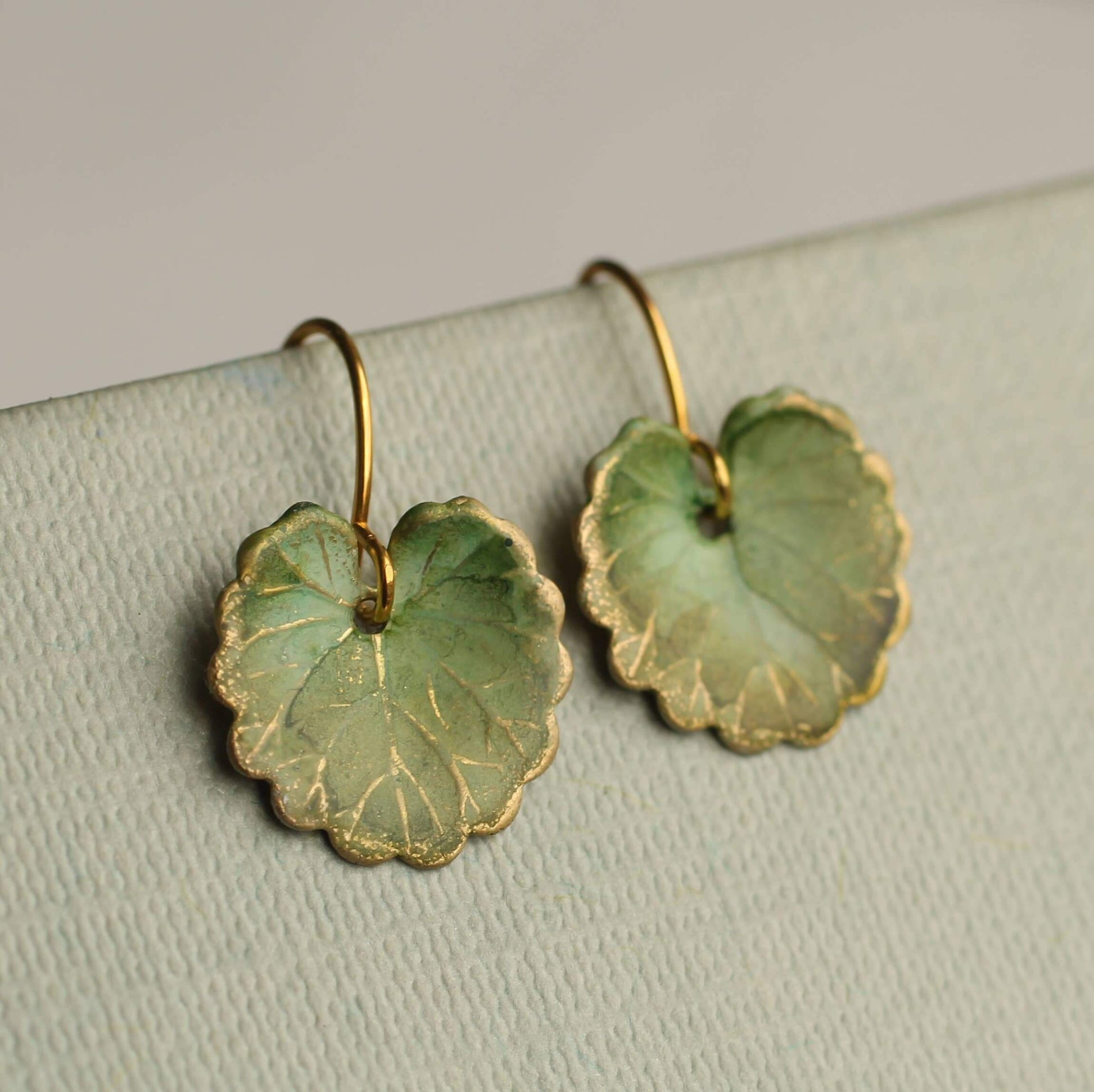 Goldfarbene Messing Ohranhänger mit olivgrünen Blatt Anhänger. Oberfläche wirkt wie ein Aquarell. Für einen natürlichen Vintage Stil.