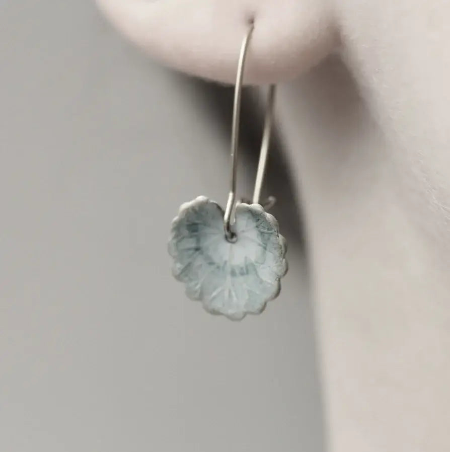 Ein schwarz weiß Bild des Ohres einer Frau. Am Ohr hängt ein Ohrring mit einem Seerosen Bllatt Anhänger. Perfekt für alle die Schmuck mit Natur Optik lieben.