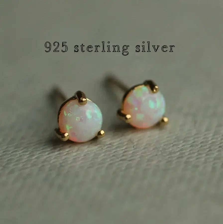 Zwei Opal Ohrstecker liegen auf einem hellgrünen Untergrund. Darüber steht der Schriftzug Sterling Silber. Die Ohrringe sind schlicht und elegant zugleich.