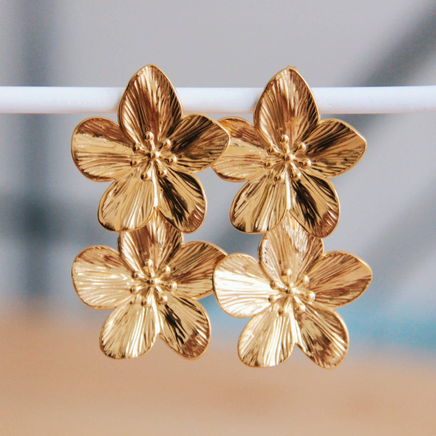 Goldfarbene Edelstahl Ohrringe mit zwei großen Kirschblüten für einen eleganten Look.