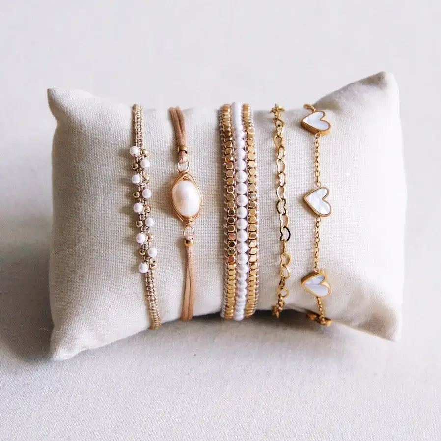 Feines Armband-Set mit weißen Herz-Anhängern auf einem Kissen, perfekt für stilvolle Looks und Kombinationen.