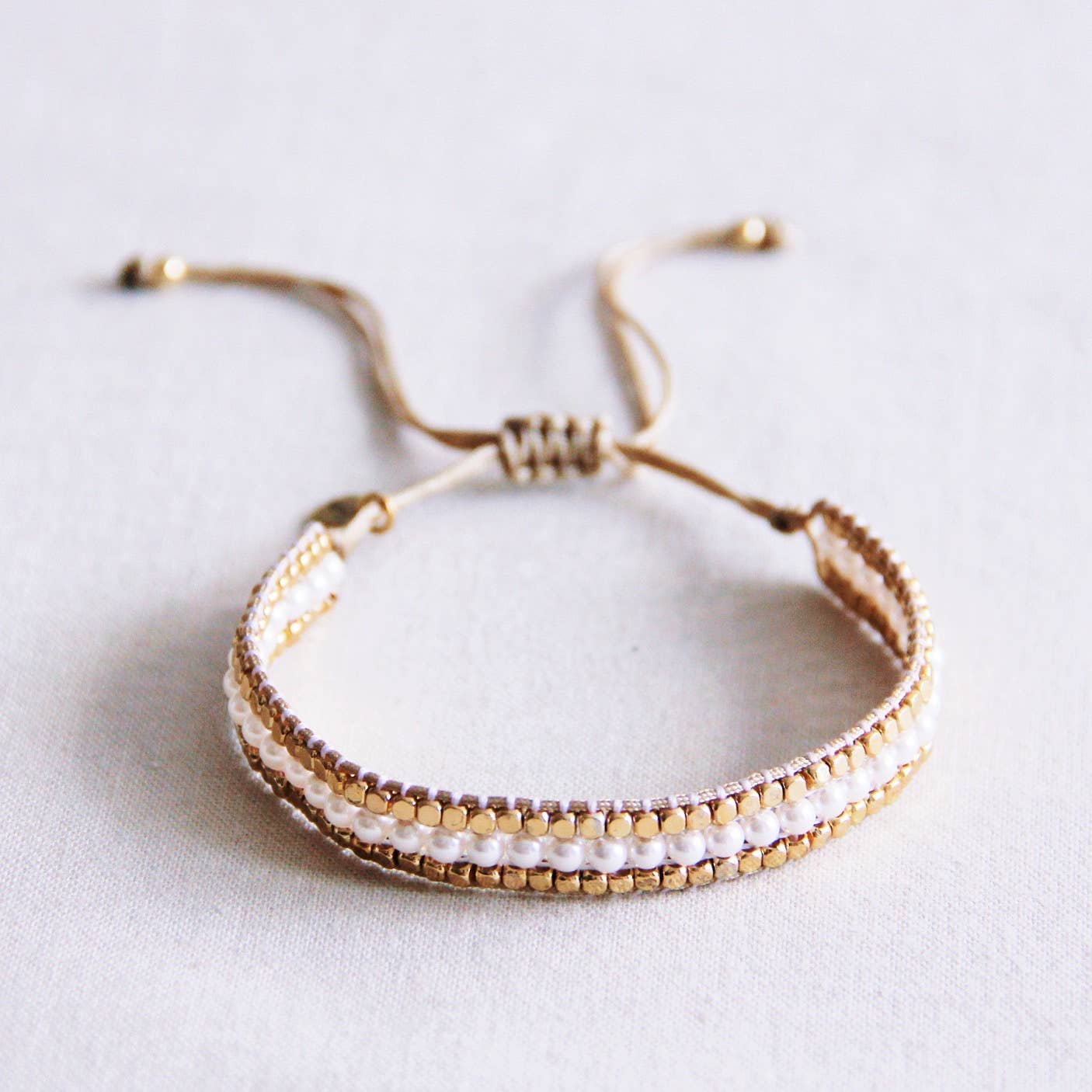 gewebtes boho perlenarmband mit edelstahl steinen und weißen perlen.