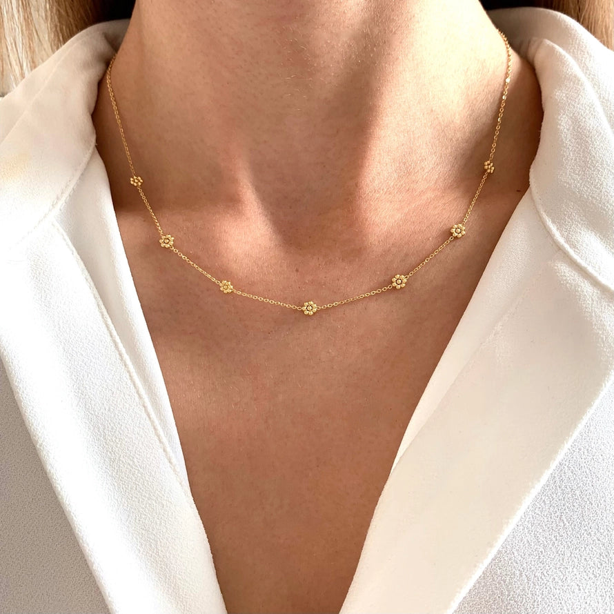 Feine Halskette aus Edelstahl mit goldenen Blumenanhängern, ideal für feminine Eleganz.