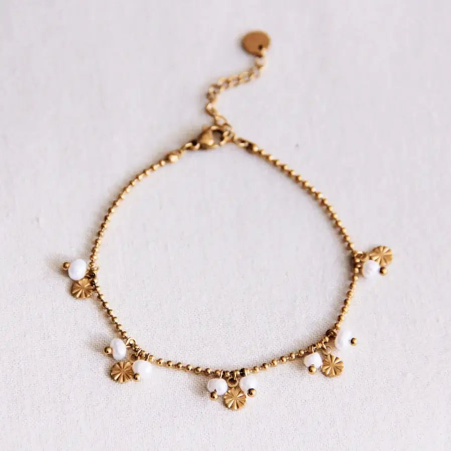 Minimalistisches Armband mit Perlen und goldenen Münzen Anhängern. Für einen minimalistischen eleganten Stil. Von oben auf einem weißen Hintergrund.
