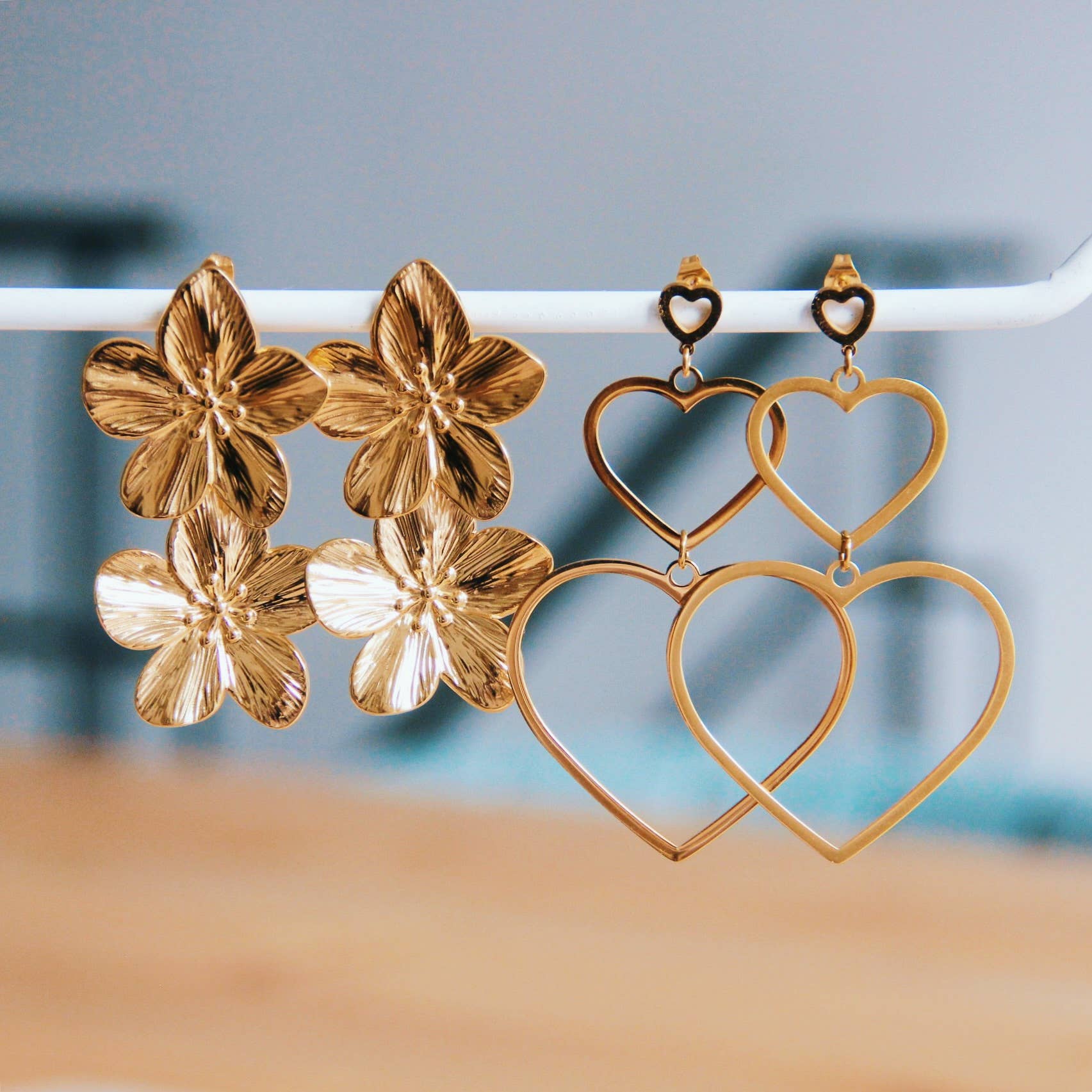 Goldfarbene Ohrringe mit zwei großen Kirschblüten und herzförmigen Elementen, ideal für elegante Looks.