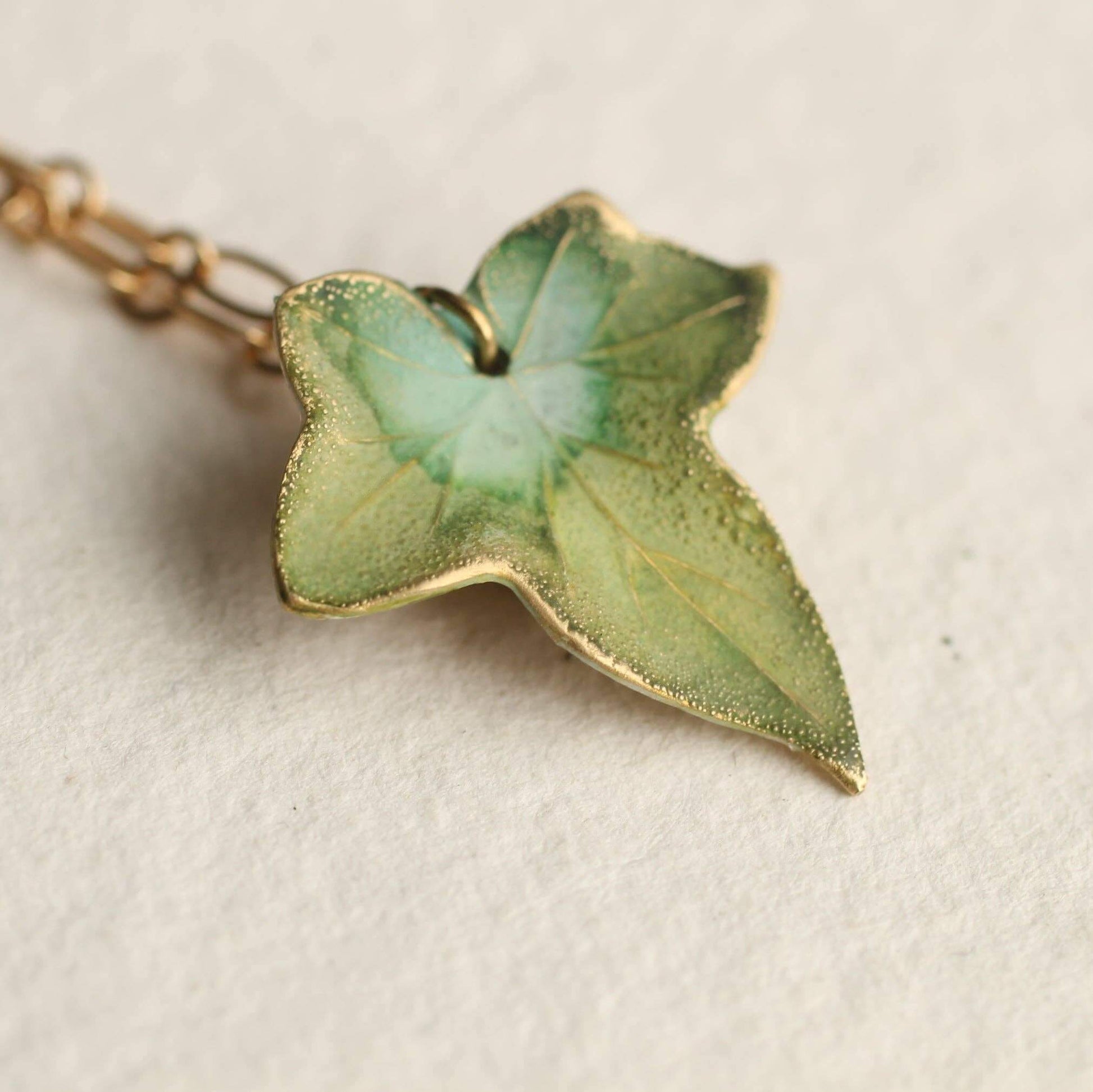 Filigrane goldfarbene Kette mit einem grünen Efeublatt Anhänger. Handgemacht mit Aquarell Optik und goldfarbenen Details.