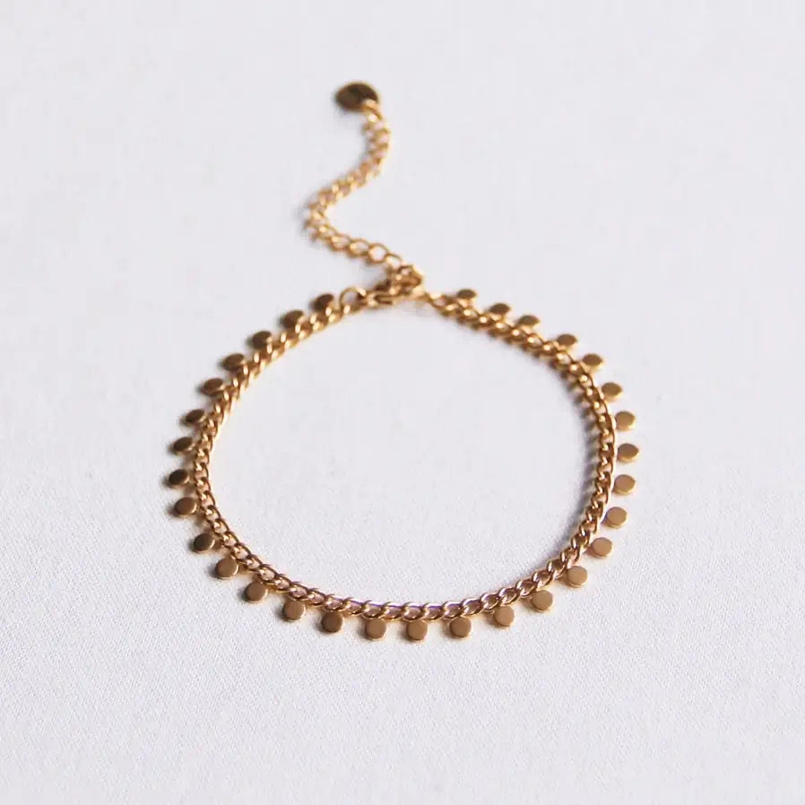 Goldfarbenes Armband aus Edelstahl mit runden Anhängern auf einem weißen Hintergrund für einen minimalistischen eleganten Look.